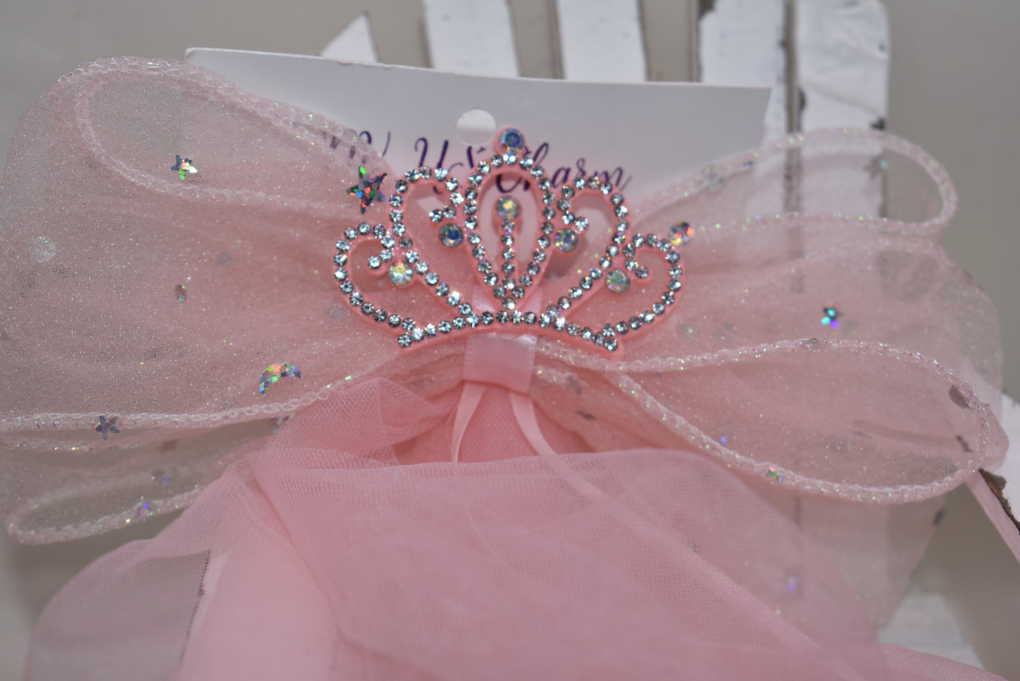 Add a touch of royalty with the Long Tail Collection 6 bow. Featuring a charming crown jewel perched atop layers of soft, flowing tulle, this easy clip-on accessory is perfect for anyone dreaming of a princess-worthy look. Effortlessly elevate any outfit with a playful sparkle that delights both kids and adults alike.