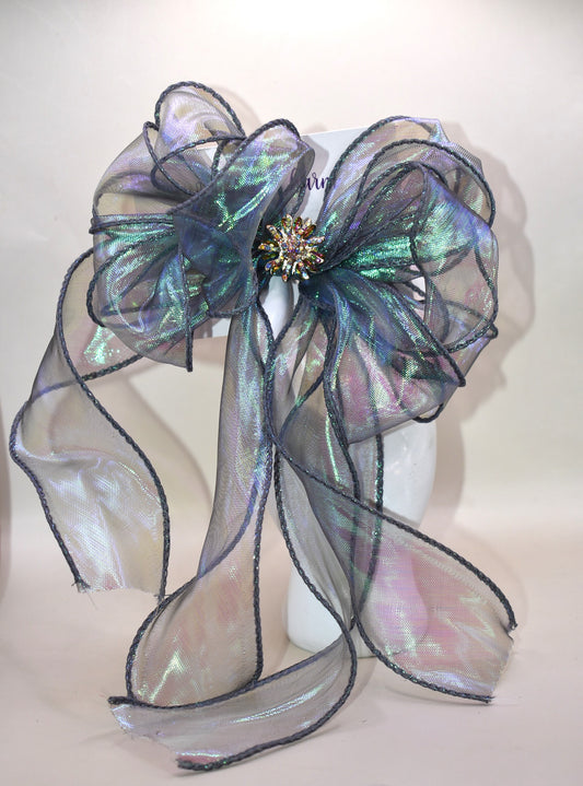 This elegant bow features an iridescent fishtail ribbon in stunning ocean hues, accented by a delicate crystal flower for a refined finish. Its long, flowing design adds graceful movement, while the wrapped alligator clip ensures a secure and comfortable fit. Perfect for adding a touch of sophistication to any look.