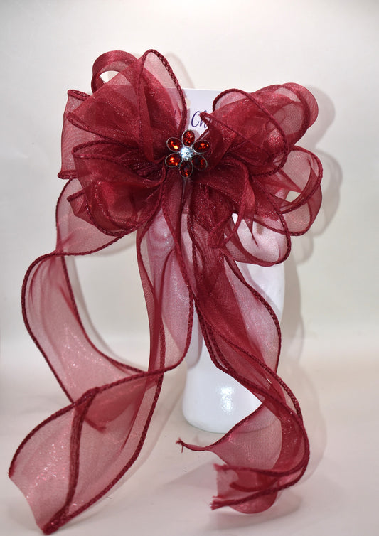 Elevate your ensemble with this elegant long burgundy bow from the Long Tail Collection. Featuring a refined fish tail ribbon design and a sparkling gem centerpiece, it adds a touch of sophistication to any outfit. Securely fastened with a wrapped alligator clip, this accessory combines style and practicality effortlessly.