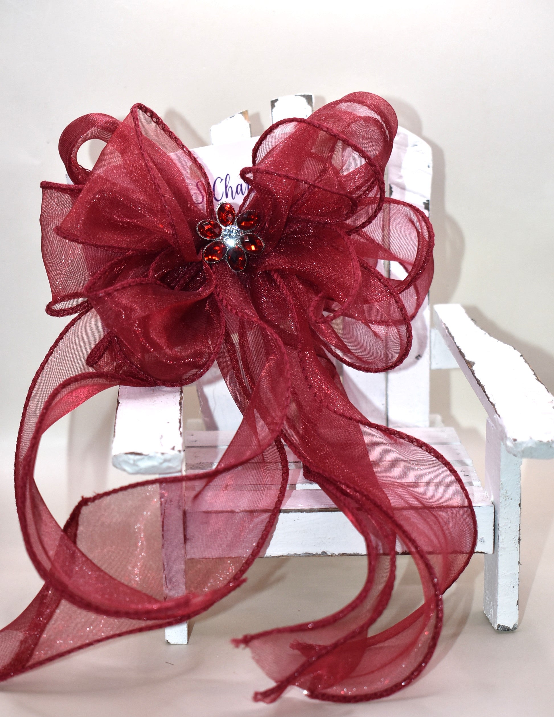 Elevate your ensemble with this elegant long burgundy bow from the Long Tail Collection. Featuring a refined fish tail ribbon design and a sparkling gem centerpiece, it adds a touch of sophistication to any outfit. Securely fastened with a wrapped alligator clip, this accessory combines style and practicality effortlessly.