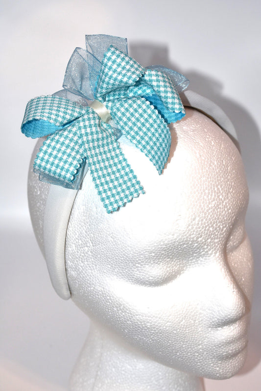 Add a splash of charm with this soft off-white headband topped with a cheerful aqua checkered ribbon. Lightweight and comfy, it’s perfect for all-day wear while adding a playful touch to any outfit.
