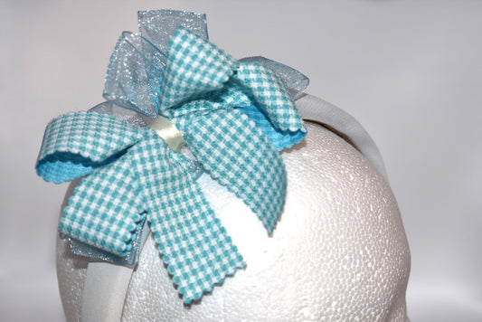 Add a splash of charm with this soft off-white headband topped with a cheerful aqua checkered ribbon. Lightweight and comfy, it’s perfect for all-day wear while adding a playful touch to any outfit.