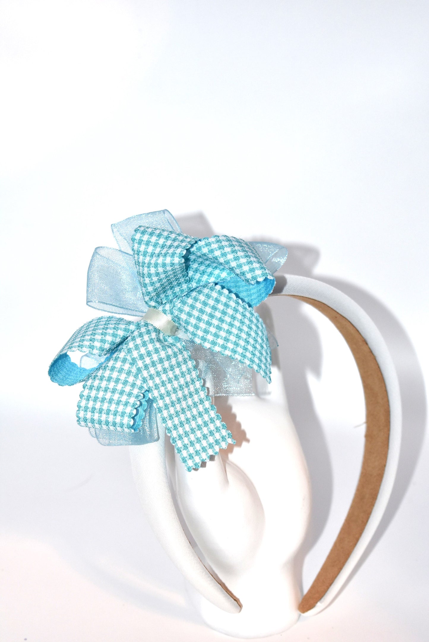 Add a splash of charm with this soft off-white headband topped with a cheerful aqua checkered ribbon. Lightweight and comfy, it’s perfect for all-day wear while adding a playful touch to any outfit.