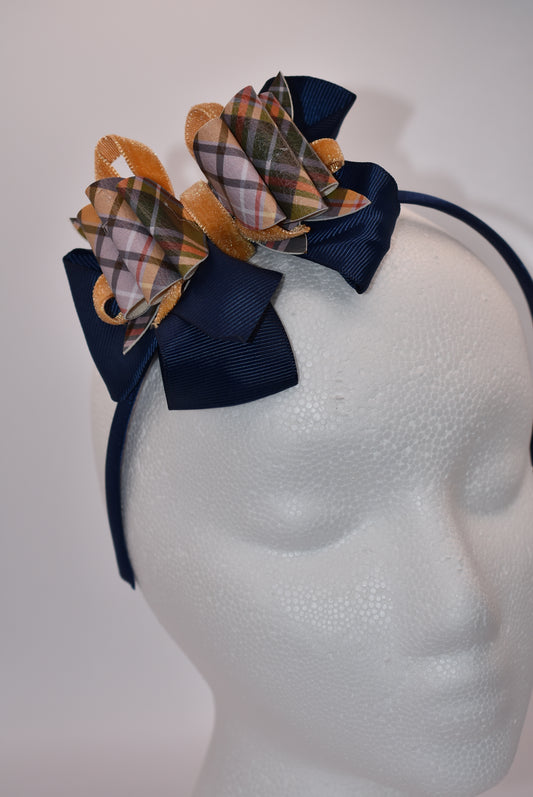 Add a splash of autumn charm with this navy blue satin headband from Nana's Headband Collection. Featuring a playful faux leather bow in gold and blue patterns layered with fun ribbons, it brings comfort and style perfectly suited for your little one’s fall adven