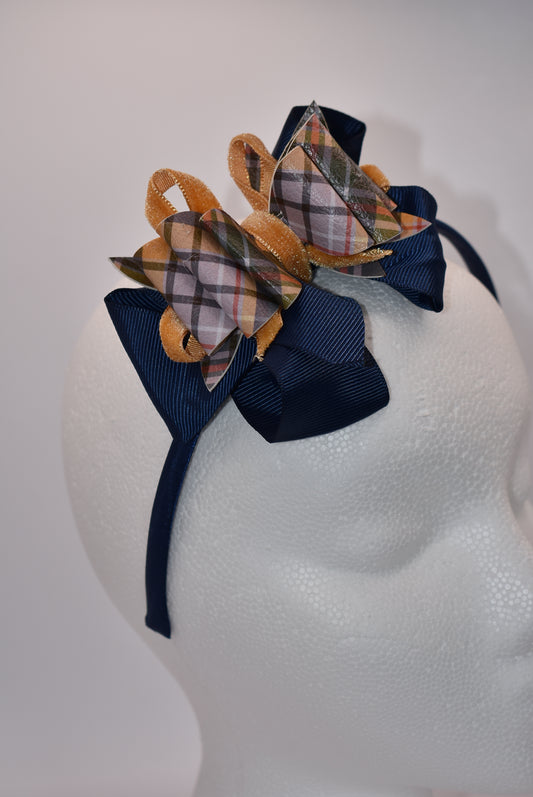Add a splash of autumn charm with this navy blue satin headband from Nana's Headband Collection. Featuring a playful faux leather bow in gold and blue patterns layered with fun ribbons, it brings comfort and style perfectly suited for your little one’s fall adven