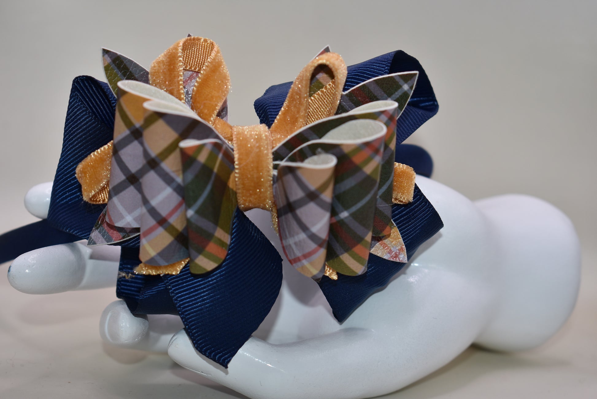 Add a splash of autumn charm with this navy blue satin headband from Nana's Headband Collection. Featuring a playful faux leather bow in gold and blue patterns layered with fun ribbons, it brings comfort and style perfectly suited for your little one’s fall adven