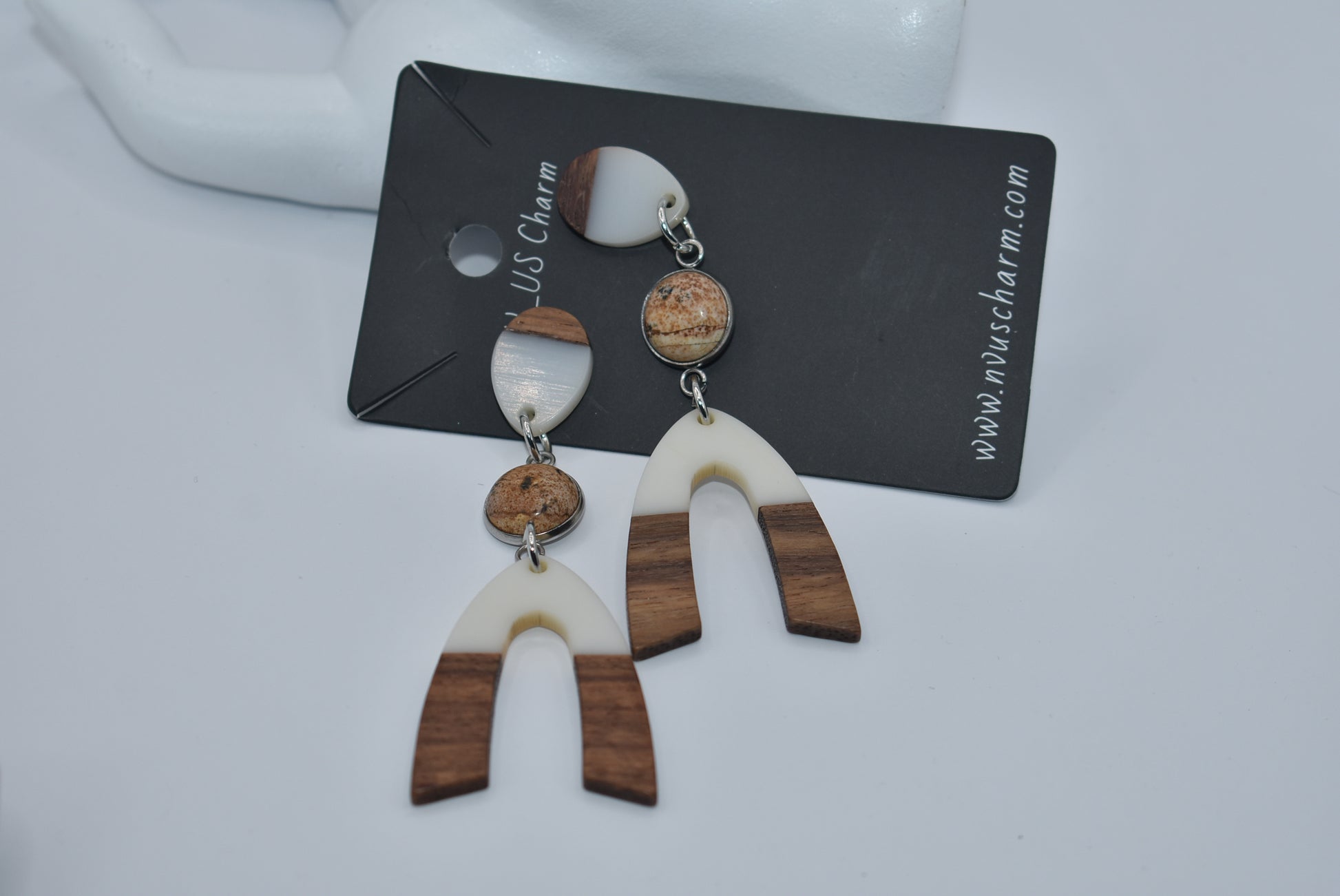 Introducing our Brown Collection earrings! Hypoallergenic, these one-of-a-kind earrings feature a natural and cream color scheme with a stunning cabochon stone in the center. Adorned with a u-shaped wood and resin charm, these earrings hang about 3 inches off the ear. A perfect finishing touch for any outfit!