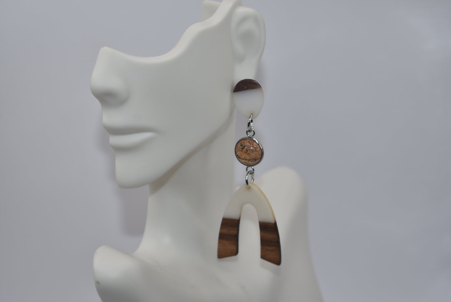 Introducing our Brown Collection earrings! Hypoallergenic, these one-of-a-kind earrings feature a natural and cream color scheme with a stunning cabochon stone in the center. Adorned with a u-shaped wood and resin charm, these earrings hang about 3 inches off the ear. A perfect finishing touch for any outfit!