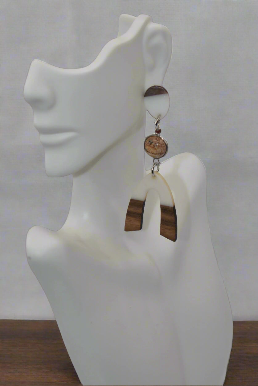 Introducing our Brown Collection earrings! Hypoallergenic, these one-of-a-kind earrings feature a natural and cream color scheme with a stunning cabochon stone in the center. Adorned with a u-shaped wood and resin charm, these earrings hang about 3 inches off the ear. A perfect finishing touch for any outfit!