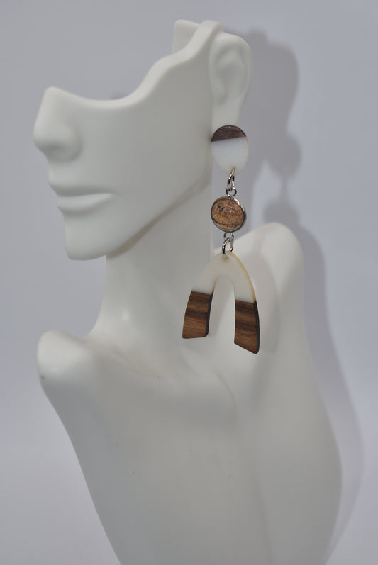 Introducing our Brown Collection earrings! Hypoallergenic, these one-of-a-kind earrings feature a natural and cream color scheme with a stunning cabochon stone in the center. Adorned with a u-shaped wood and resin charm, these earrings hang about 3 inches off the ear. A perfect finishing touch for any outfit!