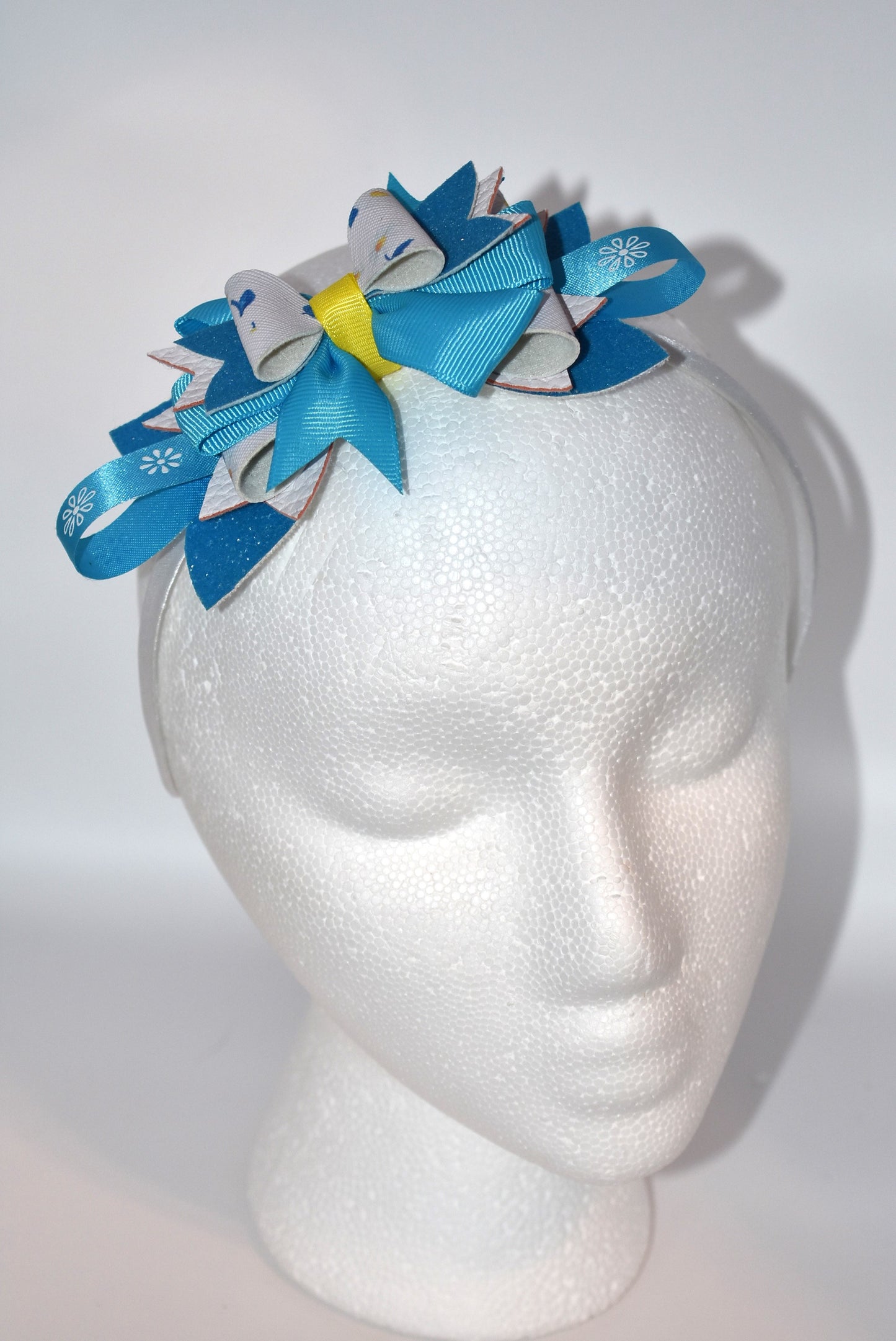 Introducing a headband that's bursting with personality! 🌸 This vibrant floral beauty features layers upon layers of alternating faux leather and satin ribbon, all wrapped around a skinny silhouette for the perfect fit. ✨ The playful mix of textures and eye-catching colors creates a one-of-a-kind accessory that's impossible to resist. 💕 Whether you're dressing up your everyday look or adding flair to a special occasion, this statement piece is sure to become your new favorite. 🎀