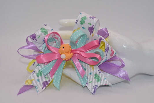 Add some prehistoric flair to any hairstyle with Nana's Collection 27! This adorable bow features multicolor layers of quality ribbon in the shape of a dinosaur, making it a playful and unique accessory. Plus, the alligator wrapped clip ensures comfortable wear all day long. Rawr!