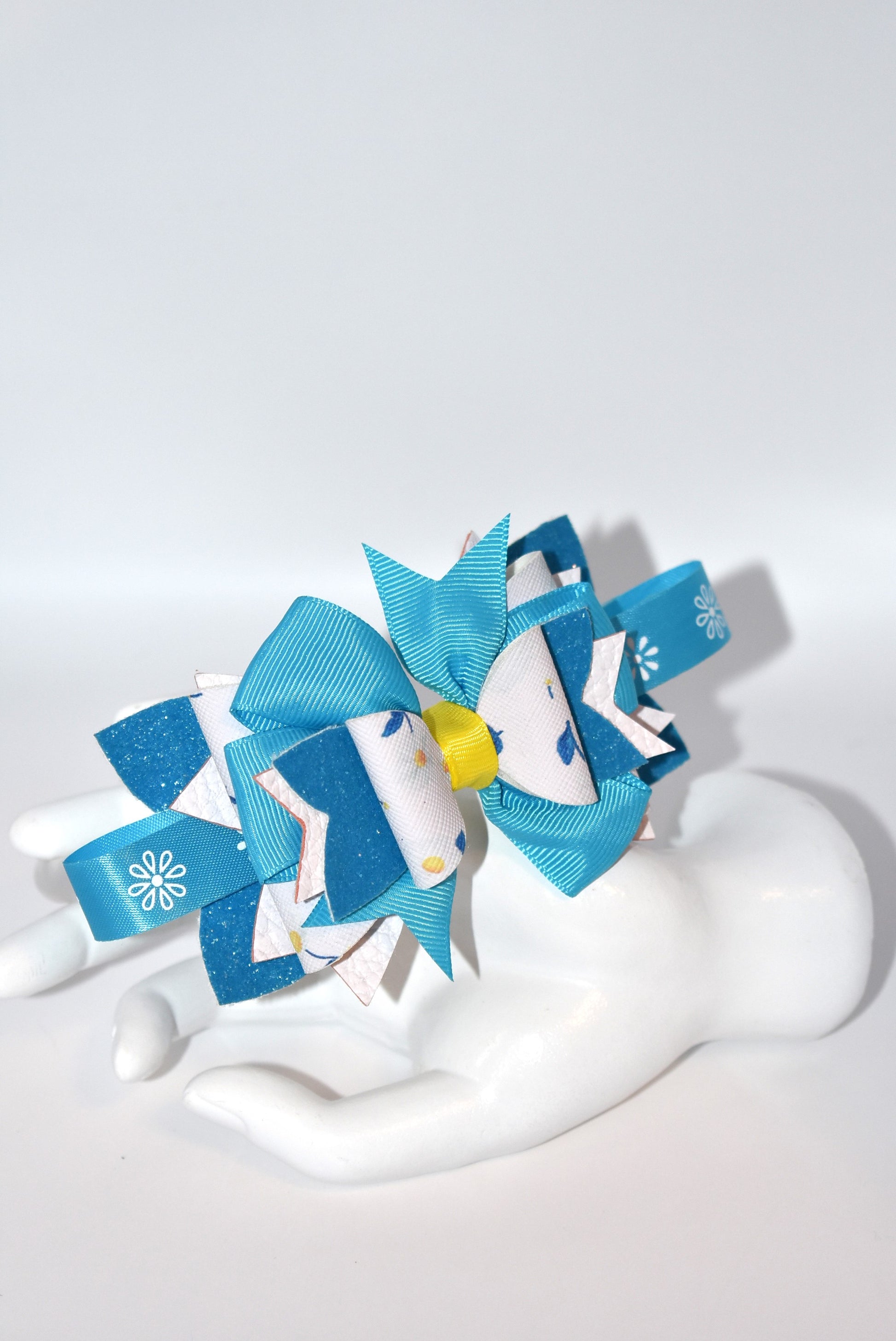 Introducing a headband that's bursting with personality! 🌸 This vibrant floral beauty features layers upon layers of alternating faux leather and satin ribbon, all wrapped around a skinny silhouette for the perfect fit. ✨ The playful mix of textures and eye-catching colors creates a one-of-a-kind accessory that's impossible to resist. 💕 Whether you're dressing up your everyday look or adding flair to a special occasion, this statement piece is sure to become your new favorite. 🎀