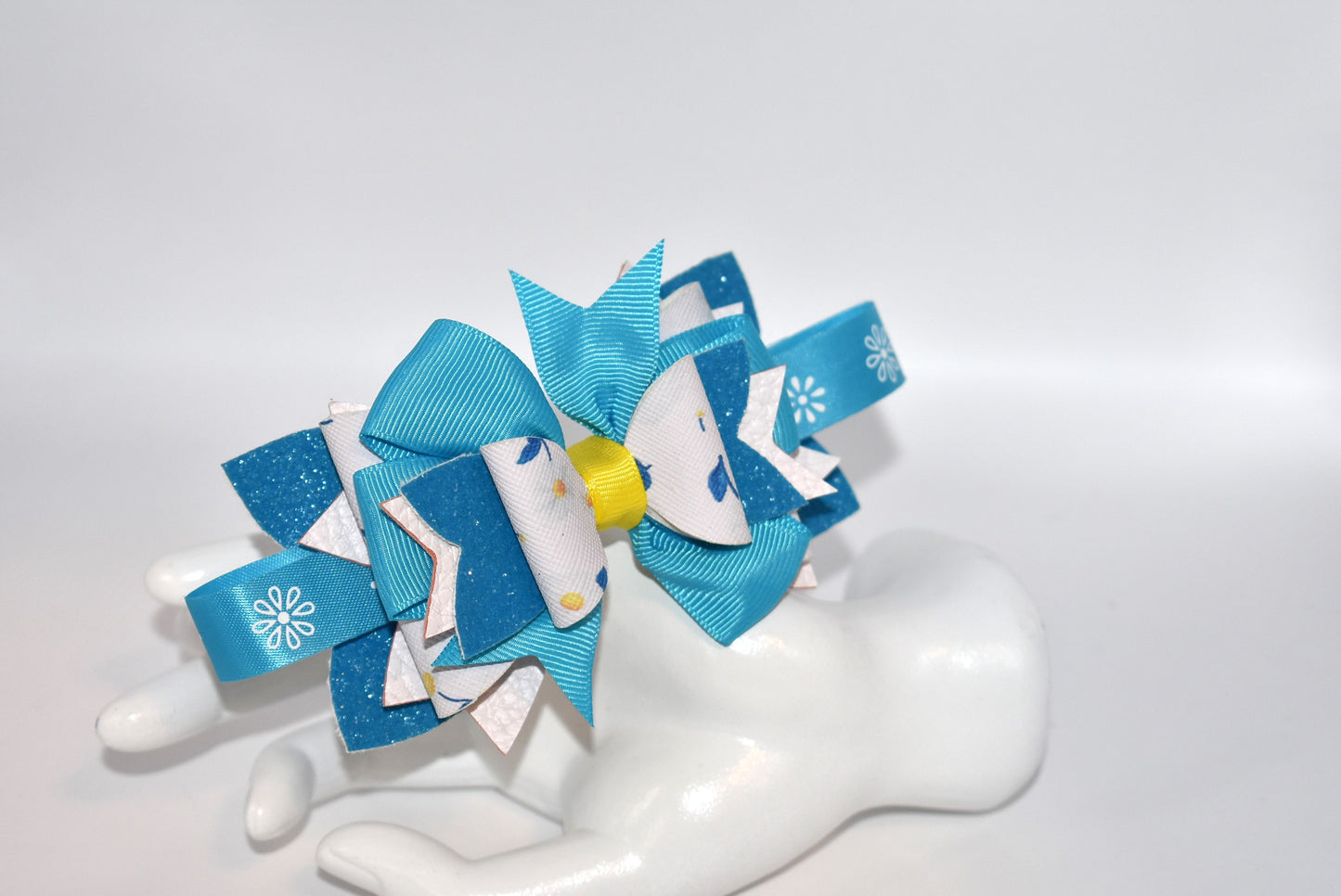 Introducing a headband that's bursting with personality! 🌸 This vibrant floral beauty features layers upon layers of alternating faux leather and satin ribbon, all wrapped around a skinny silhouette for the perfect fit. ✨ The playful mix of textures and eye-catching colors creates a one-of-a-kind accessory that's impossible to resist. 💕 Whether you're dressing up your everyday look or adding flair to a special occasion, this statement piece is sure to become your new favorite. 🎀