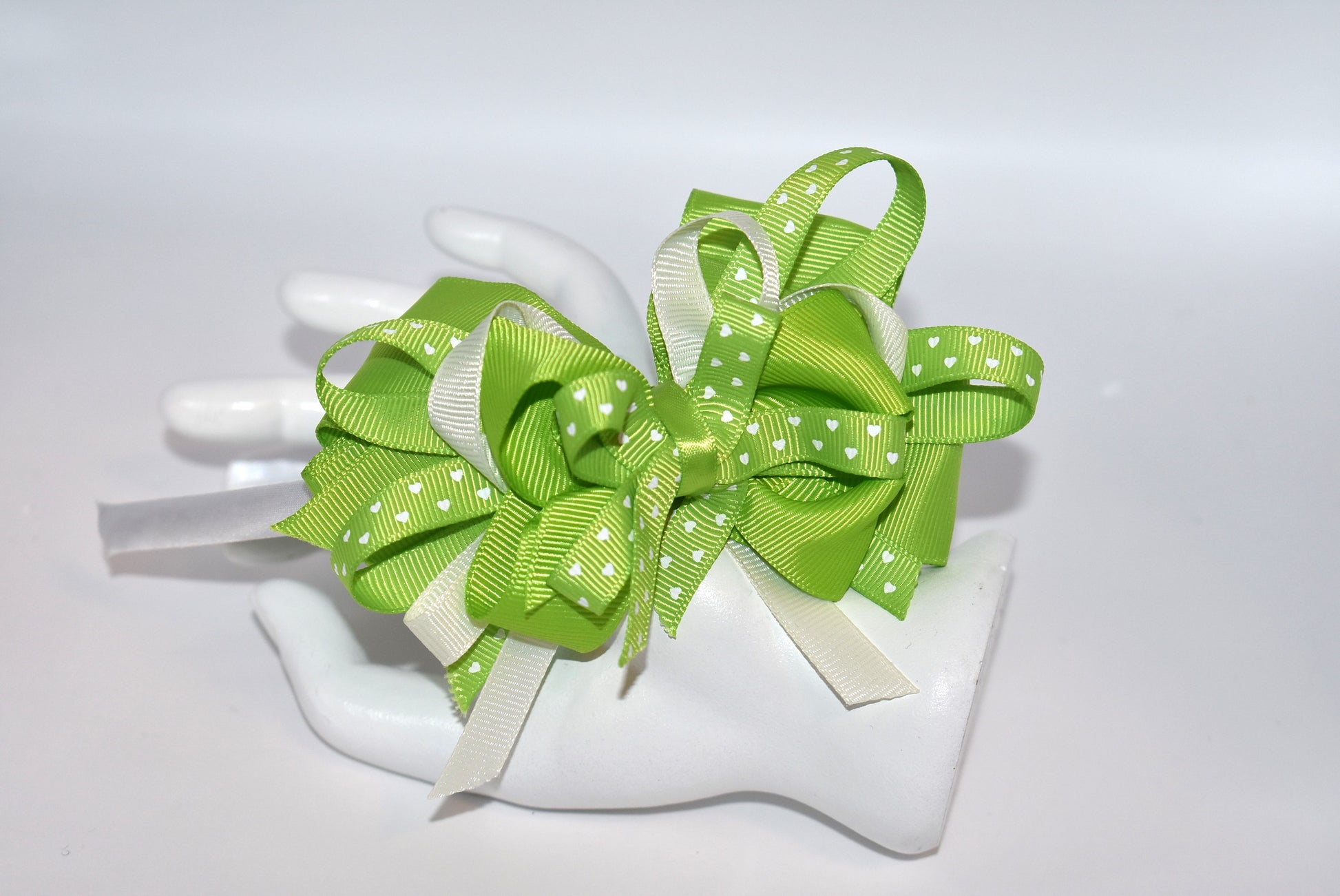 Wrap your hair in whimsy with this adorable skinny satin headband featuring layers of white and green ribbon adorned with pretty green hearts 💚 Perfect for adding a pop of color to any outfit, this lightweight design keeps you comfortable all day long without the fuss. Whether you're dressing up or keeping it casual, this charming accessory brings a playful touch to your look ✨ From Nana's Collection—where style meets sweetness! 🎀