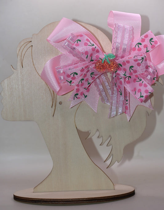 Adorable cherry-themed bow featuring delicate layers of soft pink ribbon that create a charming, dimensional look. The covered alligator clip ensures comfortable wear throughout the day without slipping or pinching. Perfect for adding a sweet pop of personality to any hairstyle, this precious accessory is designed to make you smile every time you catch your reflection. A delightful addition to Nana's Collection that celebrates timeless charm and playful style.