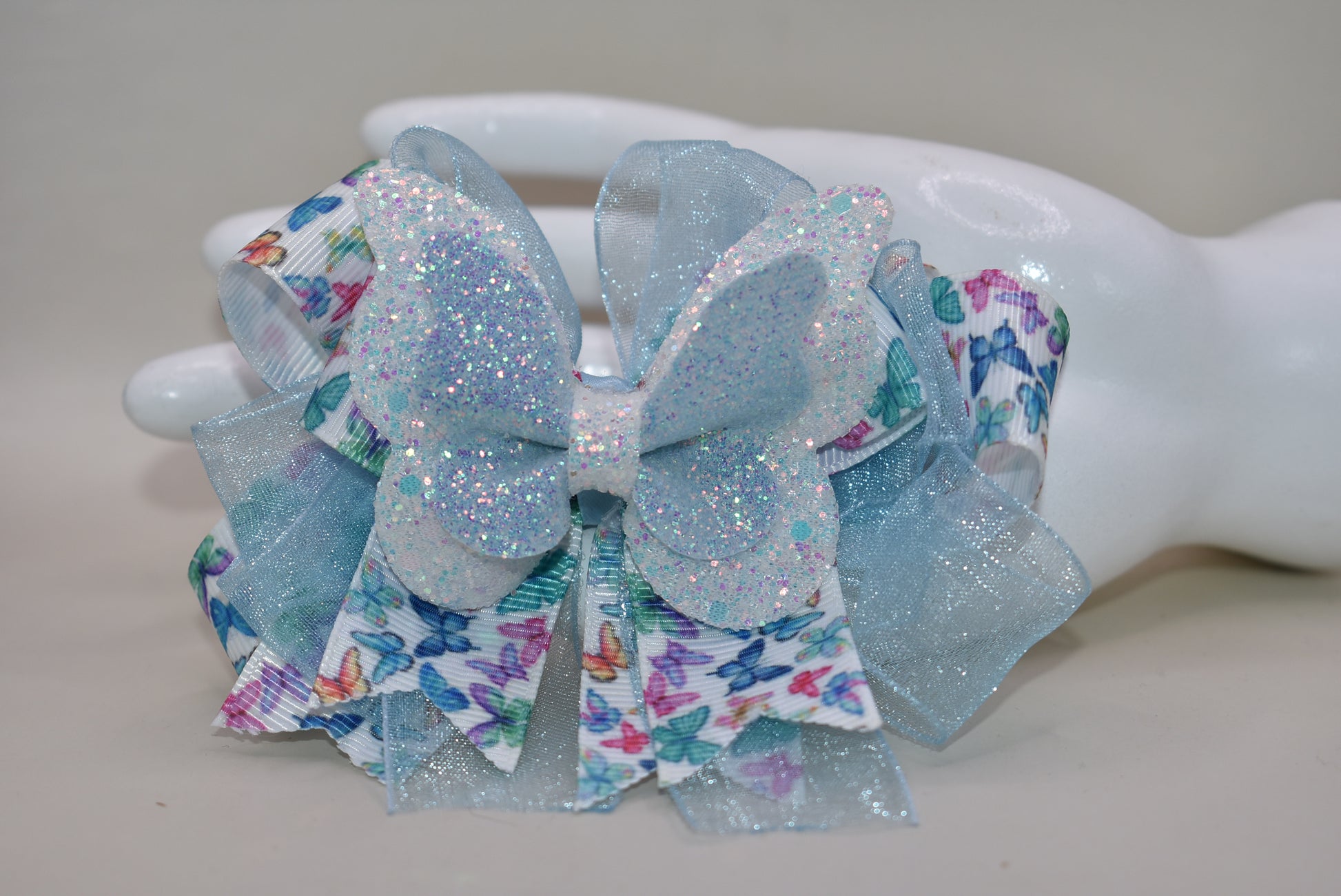 ✨ Introducing a whimsical accessory straight from Nana's Collection! This enchanting blue butterfly bow features delicate multi-colored ribbon details and luxurious layered fabric that catches the light beautifully. 🦋 The wrapped alligator clip makes it effortless to secure in your hair, keeping your style picture-perfect all day long. Perfect for adding a touch of charm and personality to any look! 💙🎀