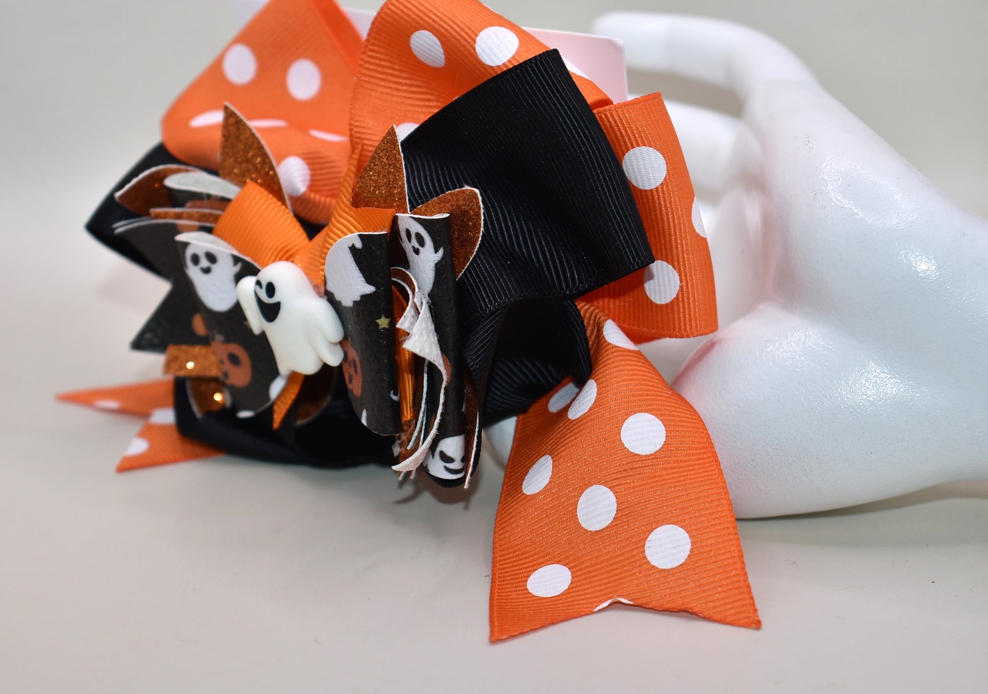 Get ready for some festive fun with this sweet and spooky clip! 🎃✨ Featuring an adorable orange polka dot ribbon paired with black and faux leather Halloween motifs, it's topped with a cute white ghost charm 👻. The wrapped alligator clip makes it super easy to wear for all your Halloween adventures!