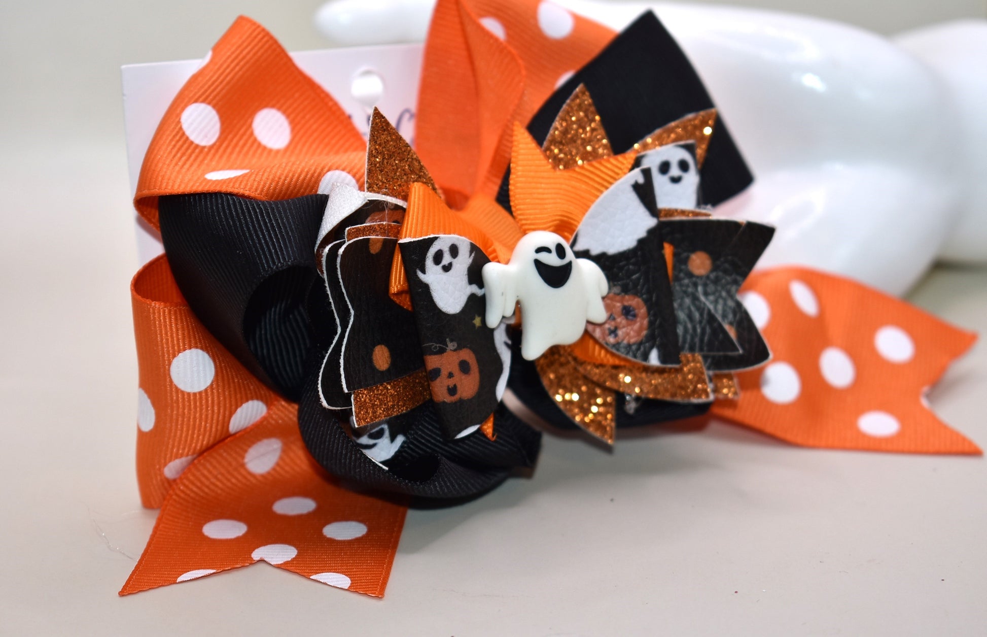Get ready for some festive fun with this sweet and spooky clip! 🎃✨ Featuring an adorable orange polka dot ribbon paired with black and faux leather Halloween motifs, it's topped with a cute white ghost charm 👻. The wrapped alligator clip makes it super easy to wear for all your Halloween adventures!