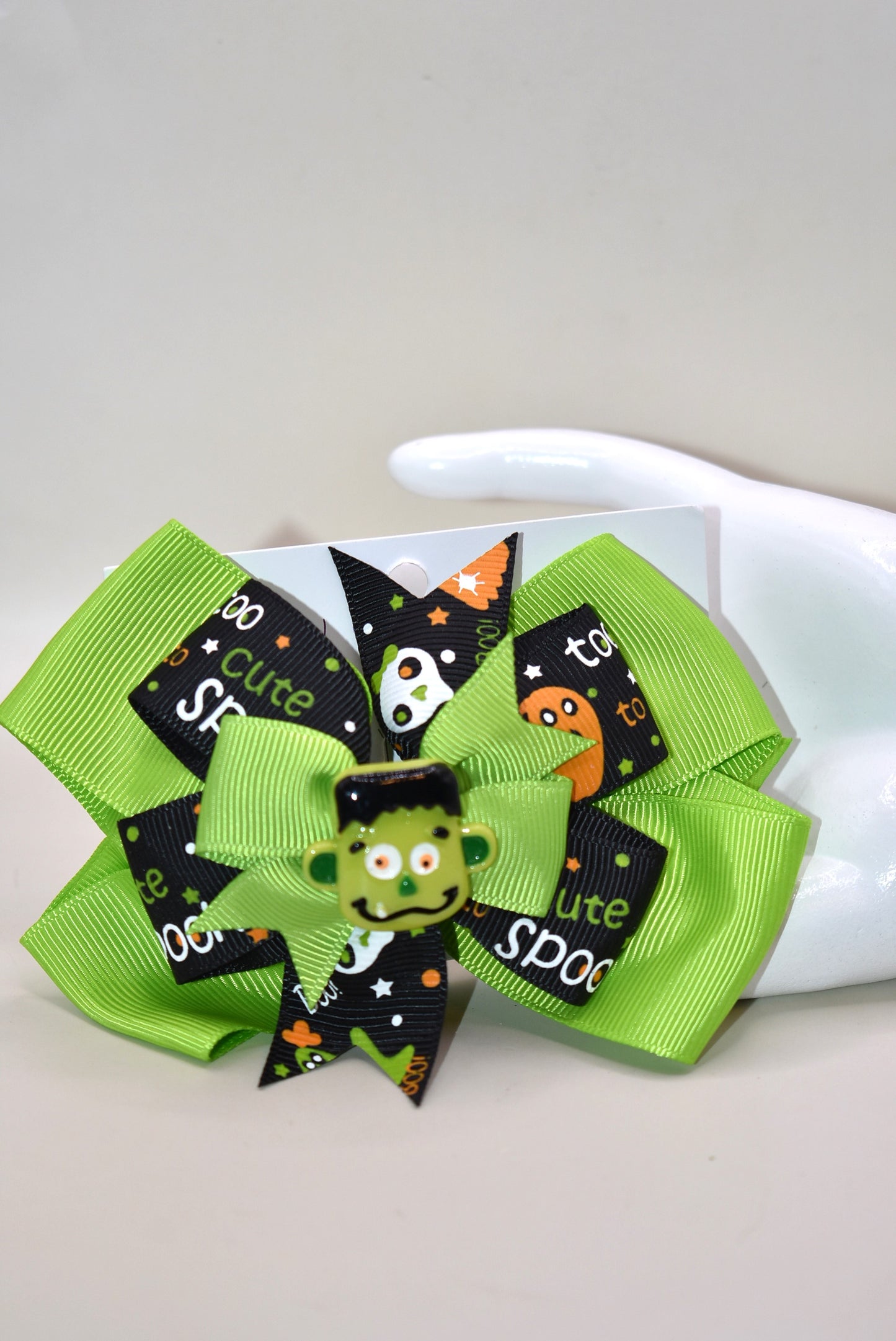 Get ready to spook in style with the cutest little Frankenstein ever! 🎃🧟♂️ Perched atop a fun green and black ribbon, this alligator clip makes wearing it a breeze. Perfect for all ages, it adds a playful touch to your Halloween look. 👻🖤💚