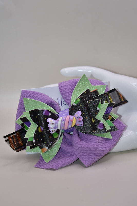 Get ready for spooky sweetness with this playful Halloween bow! 🎃 Layers of candy-inspired faux leather pop against a vibrant purple backdrop, adding a fun twist to your festive look. 🍬 Easily clip it on with a handy alligator clip for quick and comfy wear. Perfect for trick-or-treating or party fun! 🍭