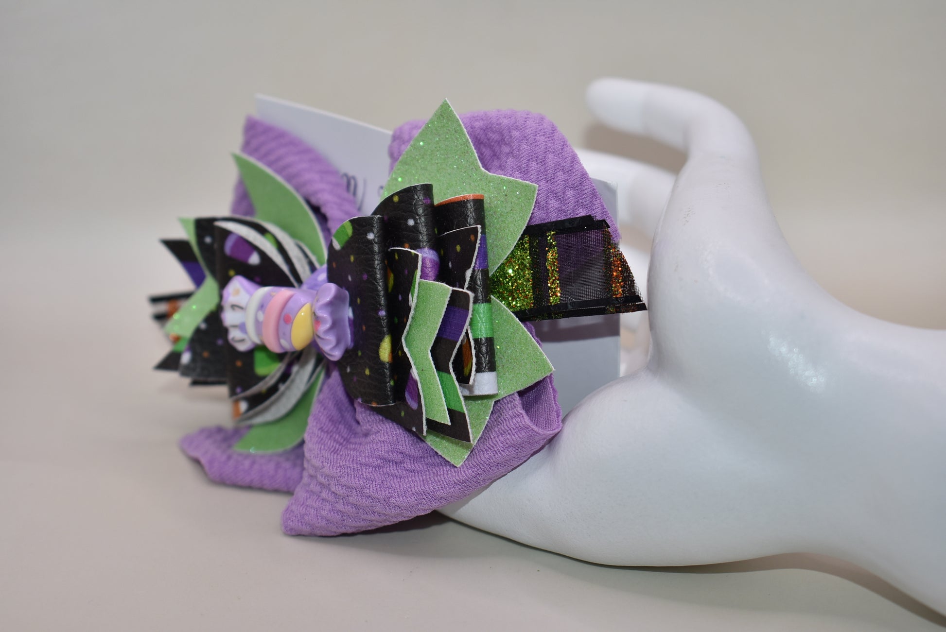 Get ready for spooky sweetness with this playful Halloween bow! 🎃 Layers of candy-inspired faux leather pop against a vibrant purple backdrop, adding a fun twist to your festive look. 🍬 Easily clip it on with a handy alligator clip for quick and comfy wear. Perfect for trick-or-treating or party fun! 🍭