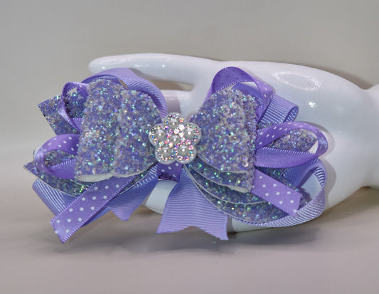 ✨ Introducing Nana's Collection – where elegance meets whimsy! 🎀 This stunning lavender bow features luxurious layers of ribbon and faux leather that create depth and dimension. A delicate flower charm sits pretty on top, adding the perfect finishing touch. 🌸 Secured with a wrapped alligator clip for effortless styling, this versatile accessory transitions seamlessly from casual to fancy. Whether you're dressing up for a special occasion or adding a pop of charm to your everyday look, this bow is your go-