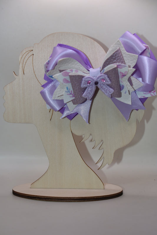 Bow lovers, rejoice! 🎀 This stunning creation features luxurious layers of ribbon and faux leather that build the perfect foundation. Topped with an adorable crocheted lavender bow adorned with sparkles ✨ for that extra touch of magic, this accessory is pure charm. The wrapped alligator clip ensures a secure, all-day hold so you can strut your stuff without worry. Perfect for adding a playful pop of personality to any look! 💜