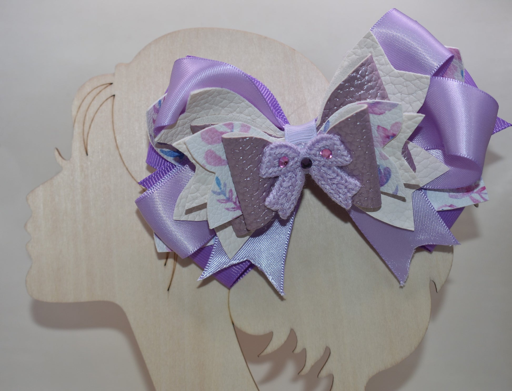 Bow lovers, rejoice! 🎀 This stunning creation features luxurious layers of ribbon and faux leather that build the perfect foundation. Topped with an adorable crocheted lavender bow adorned with sparkles ✨ for that extra touch of magic, this accessory is pure charm. The wrapped alligator clip ensures a secure, all-day hold so you can strut your stuff without worry. Perfect for adding a playful pop of personality to any look! 💜