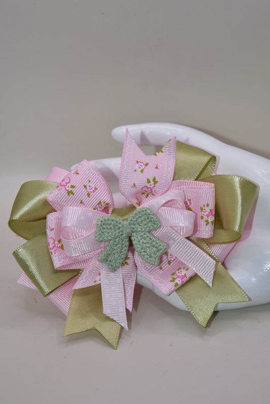 Add some fun and flair to your look with Nana's Collection 39! Featuring a playful mix of sage green and pink ribbons, topped with a cute crochet bow on a polka dot ribbon. Multiple layers of mixed ribbon make it an eye-catching accessory. Comes with a wrapped alligator clip for easy use.