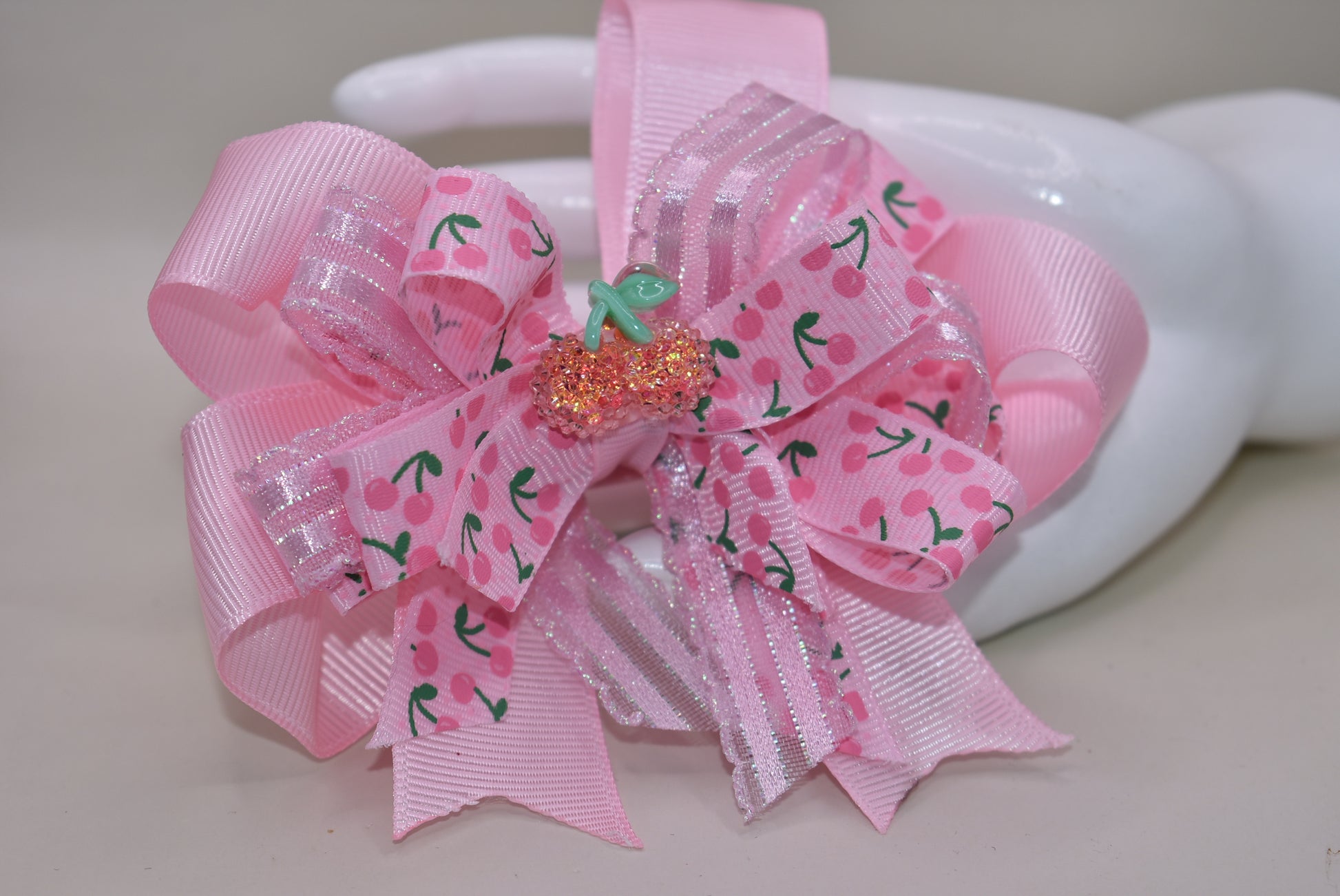 Nana's Collection 42: Add some sweet style to any outfit with the perfect cherry bow! Featuring baby pink ribbons and a sparkly cherry on top, this alligator clip ensures comfort and cuteness all day long.