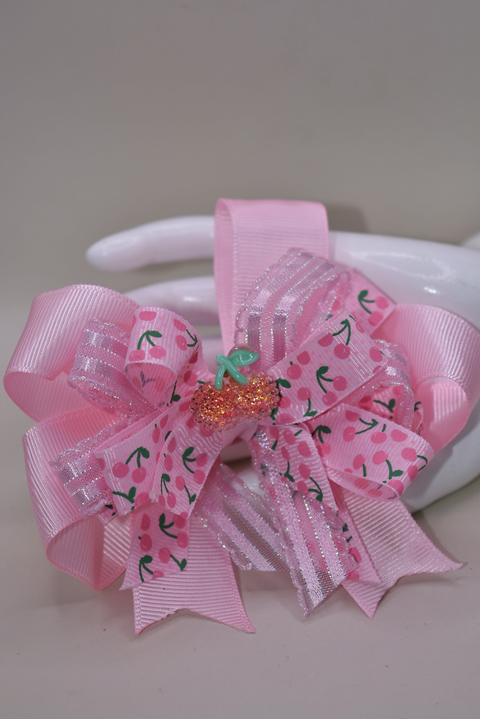 Nana's Collection 42: Add some sweet style to any outfit with the perfect cherry bow! Featuring baby pink ribbons and a sparkly cherry on top, this alligator clip ensures comfort and cuteness all day long.