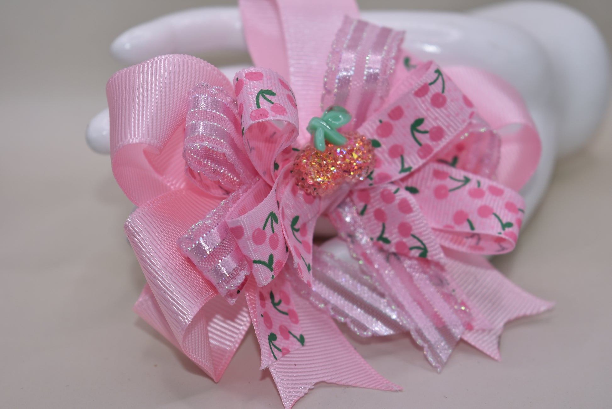 Nana's Collection 42: Add some sweet style to any outfit with the perfect cherry bow! Featuring baby pink ribbons and a sparkly cherry on top, this alligator clip ensures comfort and cuteness all day long.