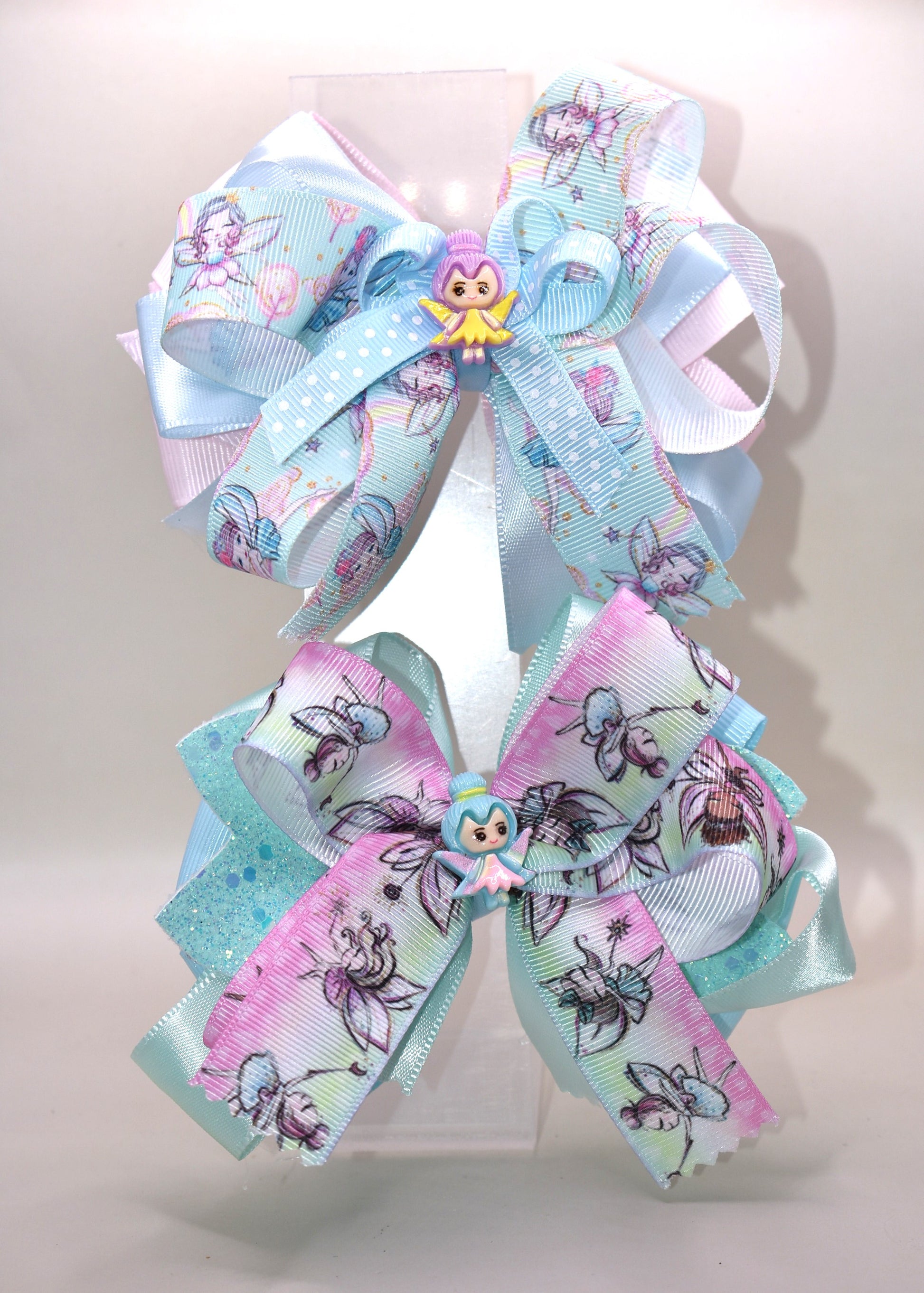 Add a touch of whimsy to any outfit with Nana's Collection 30! This darling fairy bow is made of layers of satin and grosgrain material, sure to catch the eye. Complete with a fairy ribbon and charming fairy charm, and an alligator clip for all-day comfort. Love at first sight!