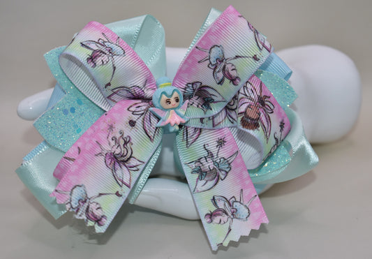 Introducing Nana's Collection 29: the perfect fairy bow that adds sparkle and layers of beautiful ribbon to any outfit. Its cute little fairy charm on top completes the adorable look. With a comfortable wrapped alligator clip, it's a must-have for any little girl's accessory collection!
