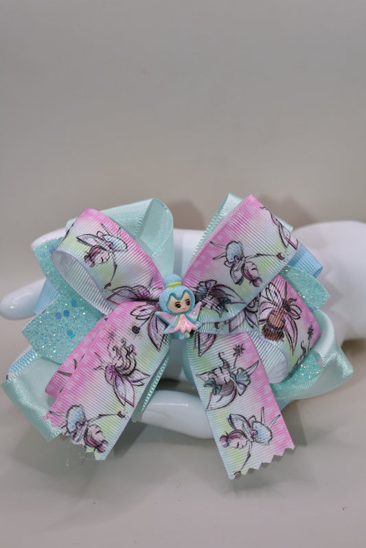 Introducing Nana's Collection 29: the perfect fairy bow that adds sparkle and layers of beautiful ribbon to any outfit. Its cute little fairy charm on top completes the adorable look. With a comfortable wrapped alligator clip, it's a must-have for any little girl's accessory collection!