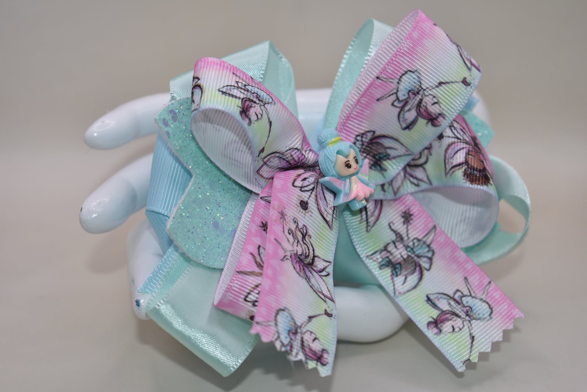 Introducing Nana's Collection 29: the perfect fairy bow that adds sparkle and layers of beautiful ribbon to any outfit. Its cute little fairy charm on top completes the adorable look. With a comfortable wrapped alligator clip, it's a must-have for any little girl's accessory collection!