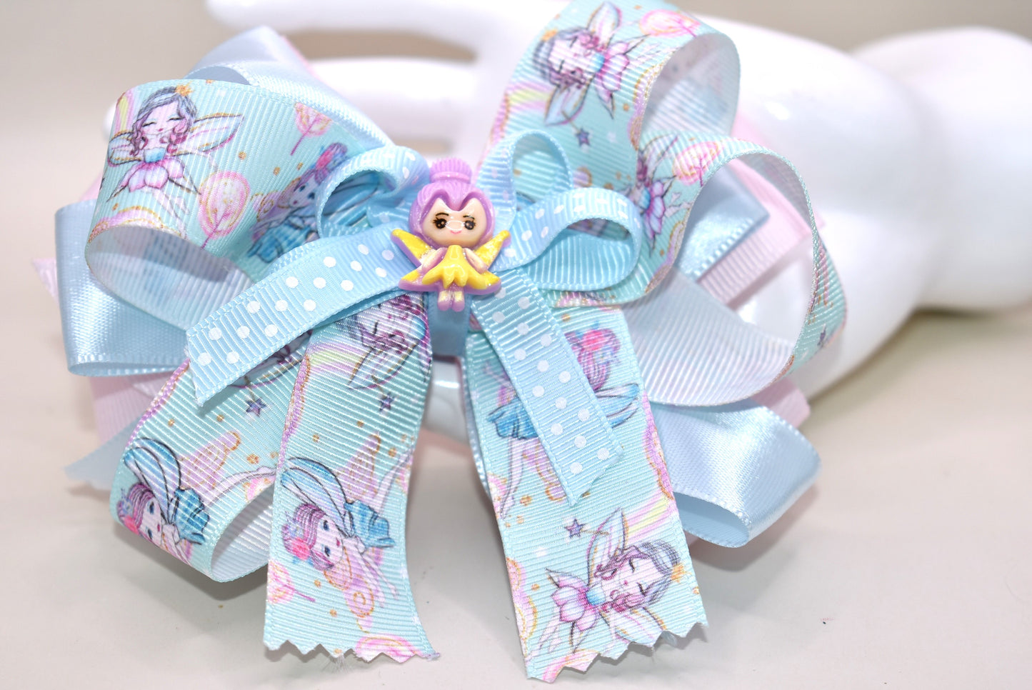 Add a touch of whimsy to any outfit with Nana's Collection 30! This darling fairy bow is made of layers of satin and grosgrain material, sure to catch the eye. Complete with a fairy ribbon and charming fairy charm, and an alligator clip for all-day comfort. Love at first sight!