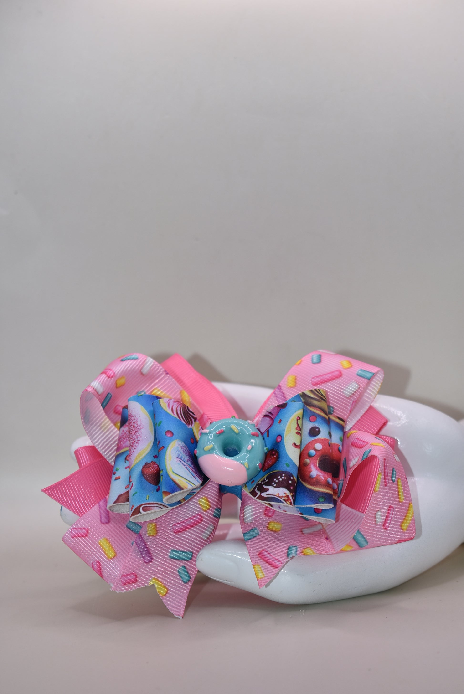 🍩 Get ready to sprinkle some sweetness into your style! This fun and colorful donut bow features layers of soft ribbon and faux leather that come together in the most adorable way. Topped with a charming donut charm, it's the perfect accessory to add a playful pop to any outfit. Whether you're dressing up for a special occasion or just want to brighten your everyday look, this delightful bow brings joy and personality to your wardrobe. 🎀✨