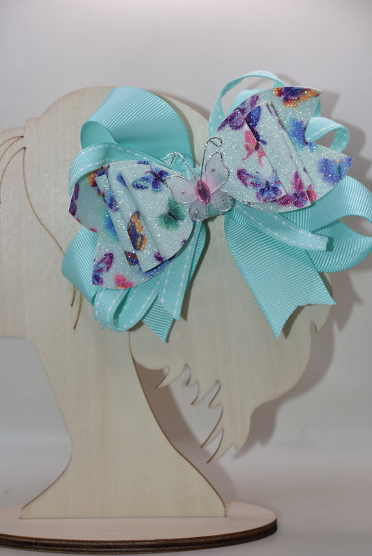 Introducing the Nana's Collection 40 – a super pretty aqua butterfly bow that's ready to flutter into your heart! 🦋✨ This charming accessory features layered butterfly-themed faux leather with a matching aqua ribbon that ties everything together beautifully. The showstopper? An absolutely gorgeous butterfly perched right on top to complete the look. Whether you're dressing up for a special occasion or adding a whimsical touch to your everyday style, this bow is the perfect finishing flourish for any outfit