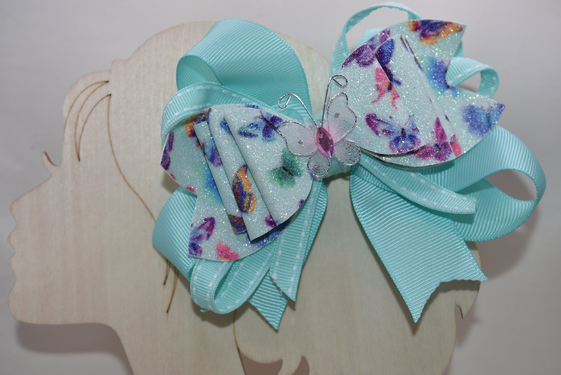 Introducing the Nana's Collection 40 – a super pretty aqua butterfly bow that's ready to flutter into your heart! 🦋✨ This charming accessory features layered butterfly-themed faux leather with a matching aqua ribbon that ties everything together beautifully. The showstopper? An absolutely gorgeous butterfly perched right on top to complete the look. Whether you're dressing up for a special occasion or adding a whimsical touch to your everyday style, this bow is the perfect finishing flourish for any outfit