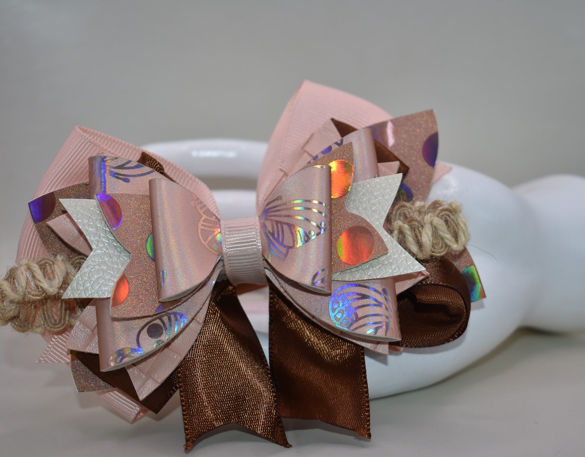 Elevate your style with this gorgeous layered bow clip! 🎀 Crafted from a chic mix of faux leather and silky ribbons in warm peach and rich brown tones, it's the perfect accessory to add personality to any look. Whether you're dressing up for a special occasion or keeping it casual, this versatile beauty works with everything. 💕 The wrapped alligator clip ensures a secure, comfortable fit all day long. ✨ A must-have piece from Nana's Collection!
