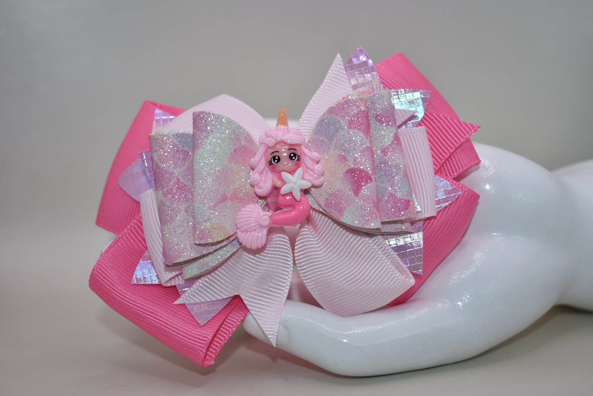 Dive into whimsy with this enchanting mermaid bow! 🧜♀️✨ Featuring layers of luxe faux leather and silky ribbon, this playful accessory is topped with an adorable pink mermaid charm that brings ocean magic to any hairstyle. The covered alligator clip ensures all-day comfort without slipping, making it perfect for little mermaids everywhere. 🎀💕 A splash of charm that's as sweet as the sea!