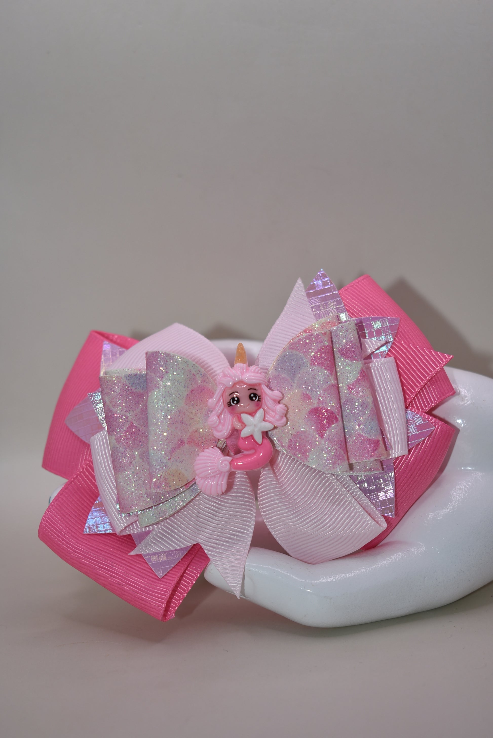 Dive into whimsy with this enchanting mermaid bow! 🧜♀️✨ Featuring layers of luxe faux leather and silky ribbon, this playful accessory is topped with an adorable pink mermaid charm that brings ocean magic to any hairstyle. The covered alligator clip ensures all-day comfort without slipping, making it perfect for little mermaids everywhere. 🎀💕 A splash of charm that's as sweet as the sea!