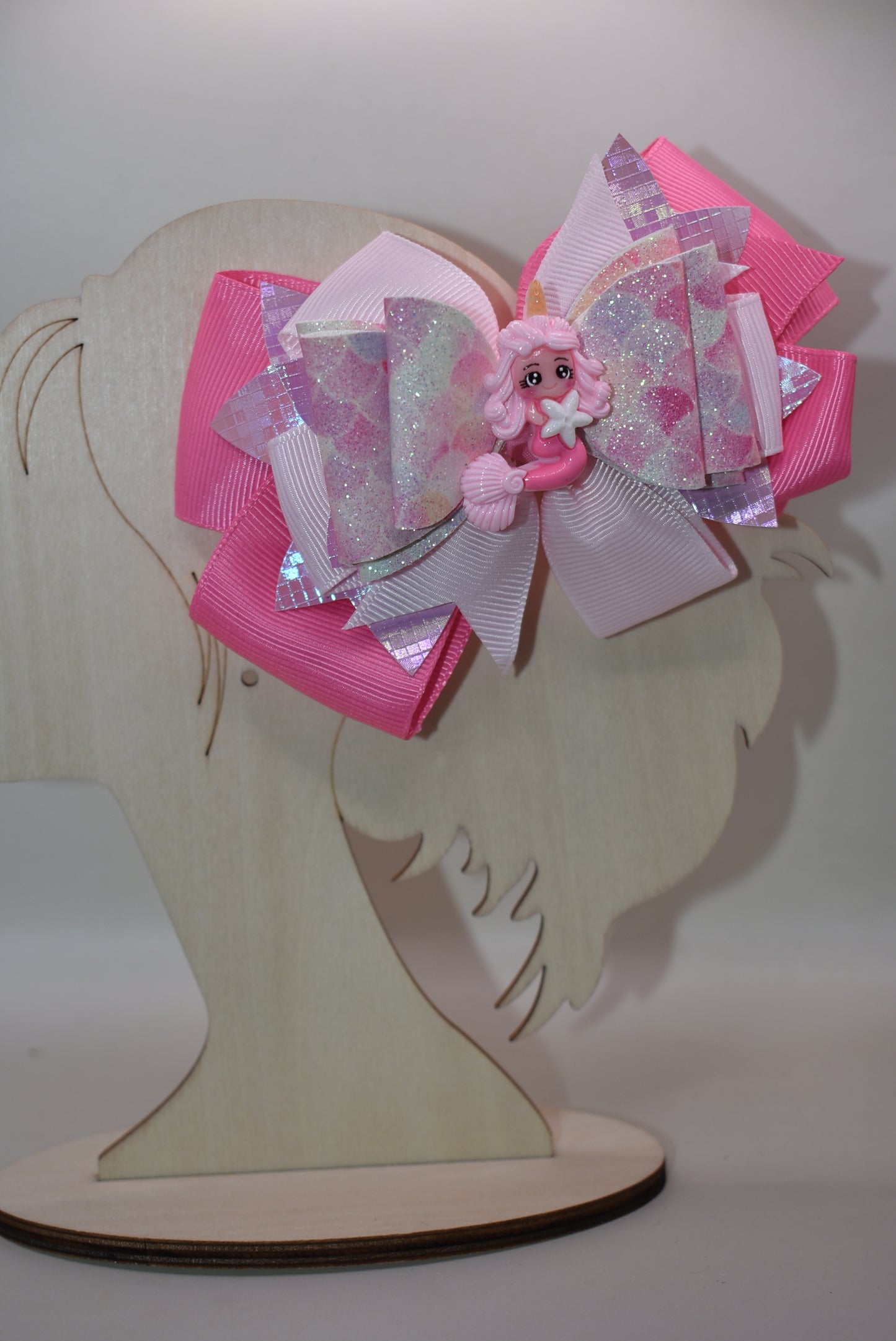 Dive into whimsy with this enchanting mermaid bow! 🧜♀️✨ Featuring layers of luxe faux leather and silky ribbon, this playful accessory is topped with an adorable pink mermaid charm that brings ocean magic to any hairstyle. The covered alligator clip ensures all-day comfort without slipping, making it perfect for little mermaids everywhere. 🎀💕 A splash of charm that's as sweet as the sea!