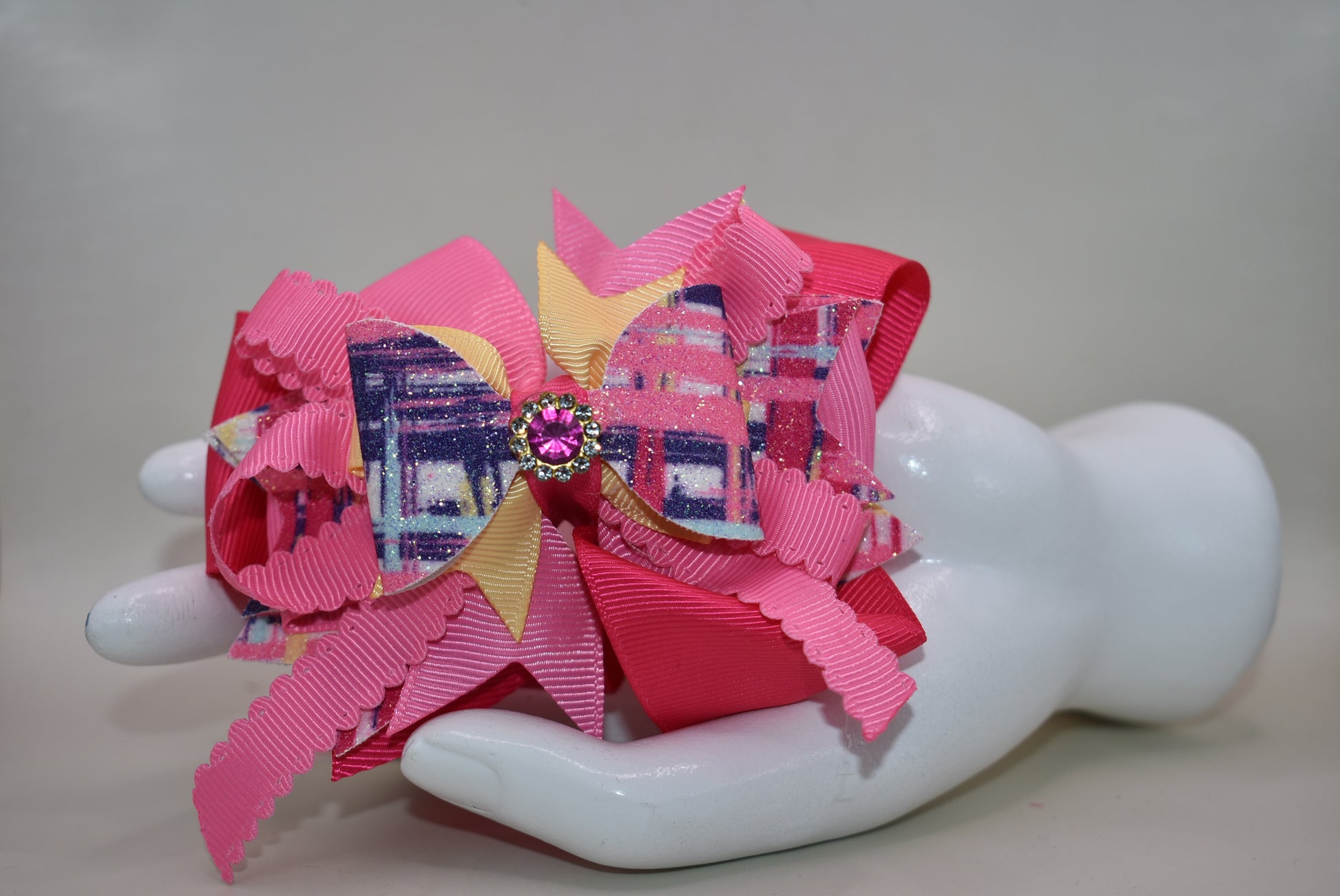 Get ready to turn heads with this super fun accessory! 💕 Nana's Collection 56 features vibrant pink layers of ribbon and faux leather that stack up for maximum style impact. A adorable pink gem sparkles from the top, adding that extra touch of sparkle and charm. ✨ Secured with a wrapped alligator clip, it's both secure and seriously cute. Perfect for adding a pop of personality to any hairstyle! 🎀