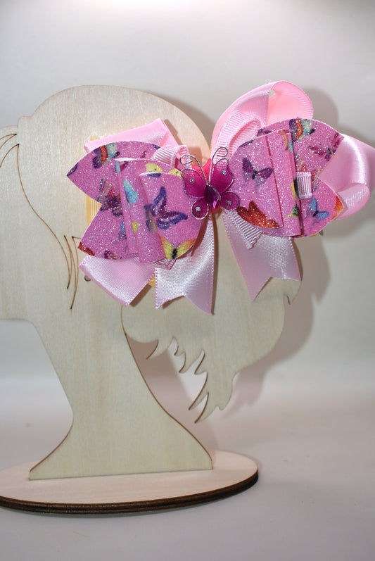 ✨ Introducing the prettiest addition to your hair collection! This adorable pink butterfly bow features layers of mixed faux leather and ribbon that create dimension and charm. A delicate butterfly charm sits proudly on top, adding that extra touch of whimsy. 🦋 The wrapped alligator clip keeps your style secure all day long, so you can twirl and play without worry. Perfect for adding a pop of personality to any look! 💕