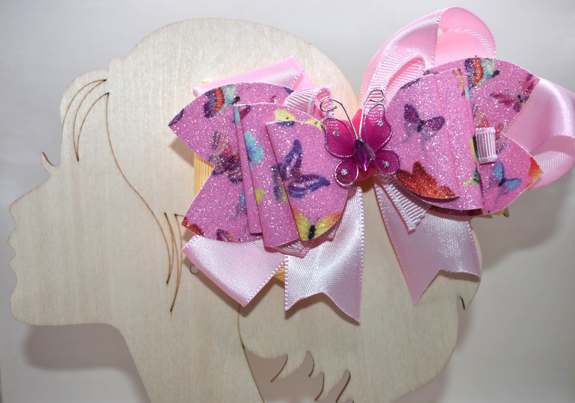 ✨ Introducing the prettiest addition to your hair collection! This adorable pink butterfly bow features layers of mixed faux leather and ribbon that create dimension and charm. A delicate butterfly charm sits proudly on top, adding that extra touch of whimsy. 🦋 The wrapped alligator clip keeps your style secure all day long, so you can twirl and play without worry. Perfect for adding a pop of personality to any look! 💕