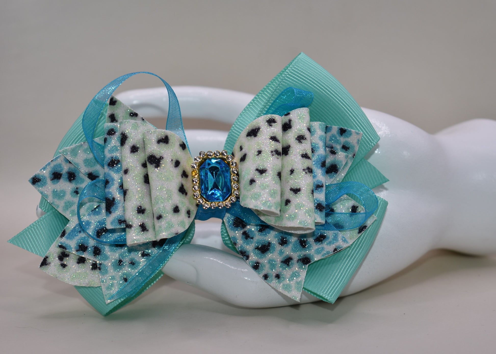 Get ready to roar! 🐆 This fabulous leopard print hair clip features multi-layered ribbon and faux leather details that bring serious style to your look. The wrapped alligator clip on back makes it super easy to secure your hair in place, while a gorgeous aqua gem sparkles on top for that perfect pop of fun. ✨ Time to unleash your wild side! 💎