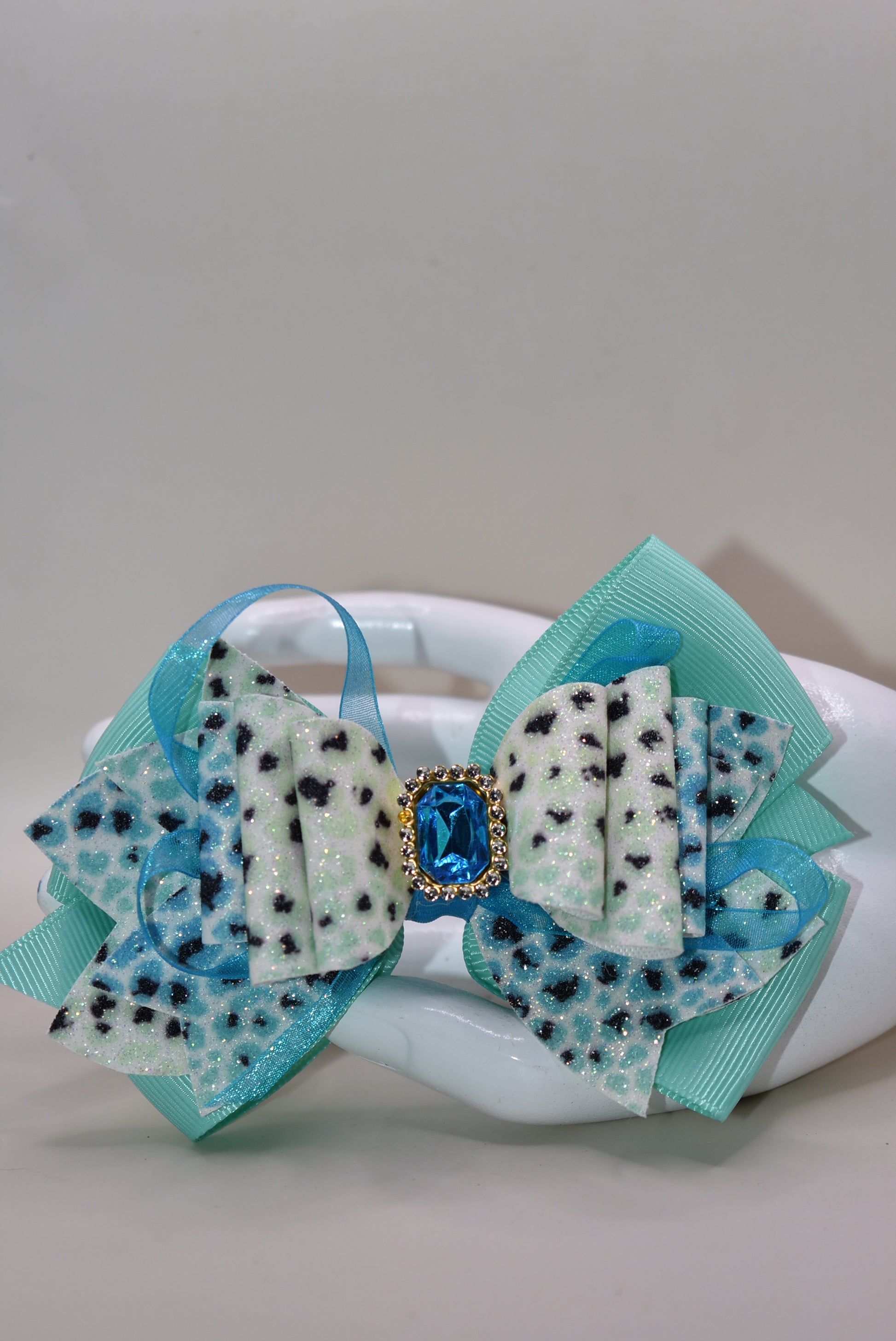 Get ready to roar! 🐆 This fabulous leopard print hair clip features multi-layered ribbon and faux leather details that bring serious style to your look. The wrapped alligator clip on back makes it super easy to secure your hair in place, while a gorgeous aqua gem sparkles on top for that perfect pop of fun. ✨ Time to unleash your wild side! 💎